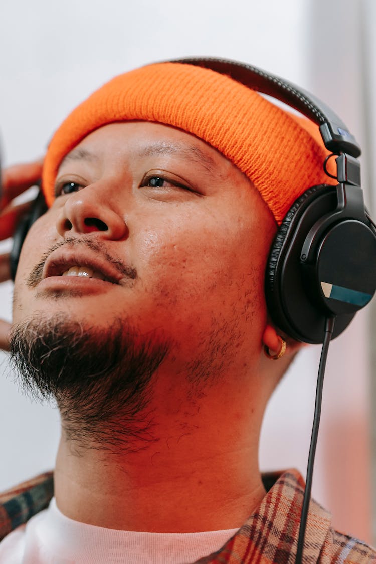 Man Wearing An Orange Beanie Hat And Black Headphones