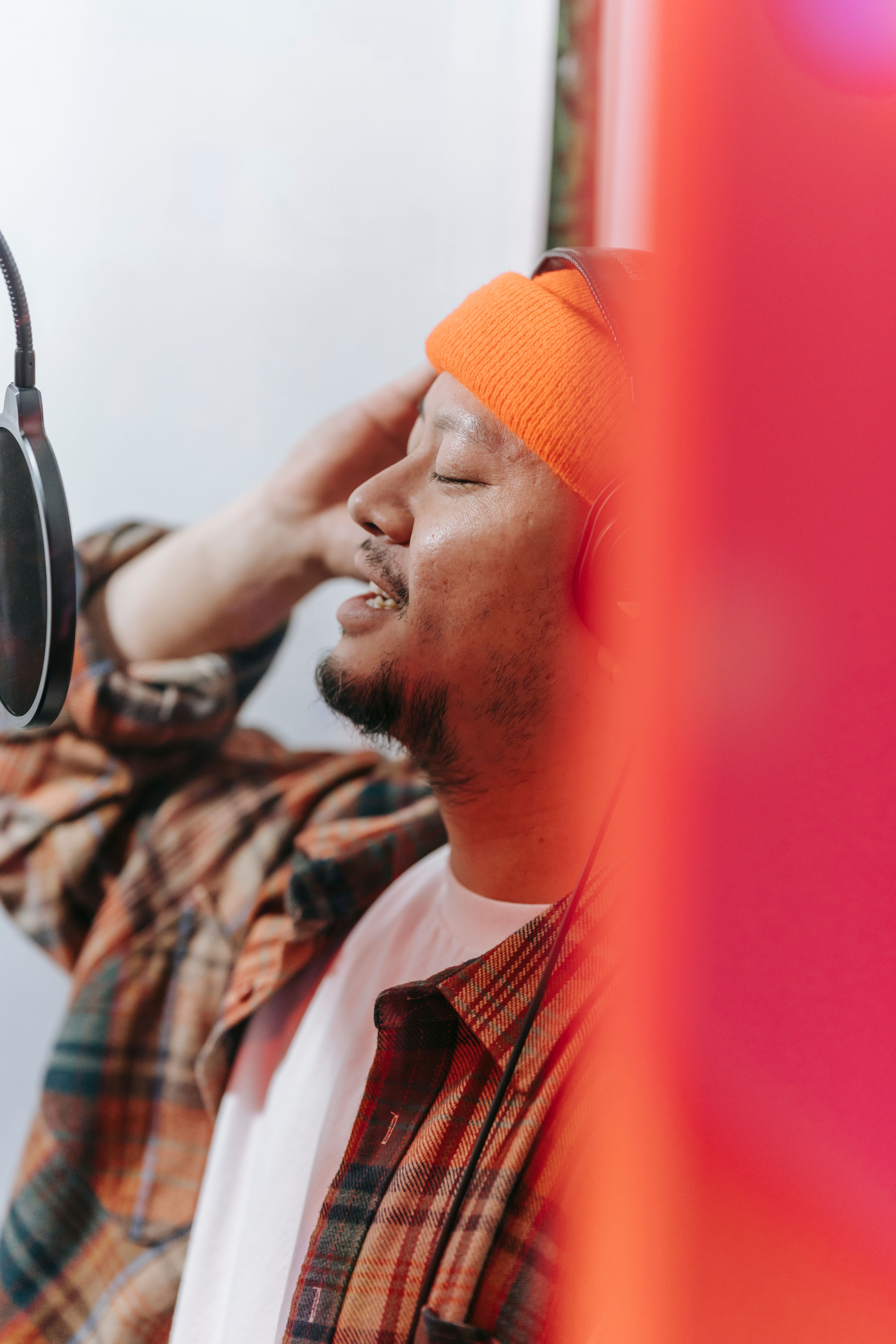 A male musician passionately singing into a microphone in a modern music studio.