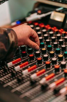 A close-up of a DJ mixing music with a hand on a soundboard showcasing modern technology.