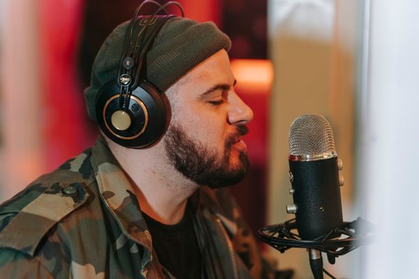 Bearded vocalist with headphones singing into a studio microphone