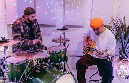 Two musicians playing drums and guitar in an indoor studio setting.
