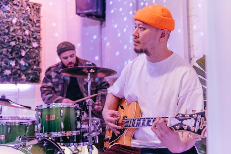 Two Men In Hats Playing Guitar And Drums