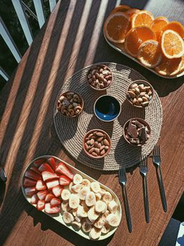 Top view of a vibrant assortment of fruits and nuts beautifully displayed on a wooden table, perfect for a healthy snack.