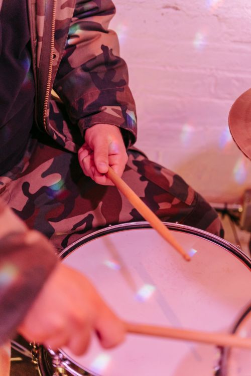 Free A drummer's hands playing on a snare drum under colorful lights, showcasing a close-up musical moment. Stock Photo