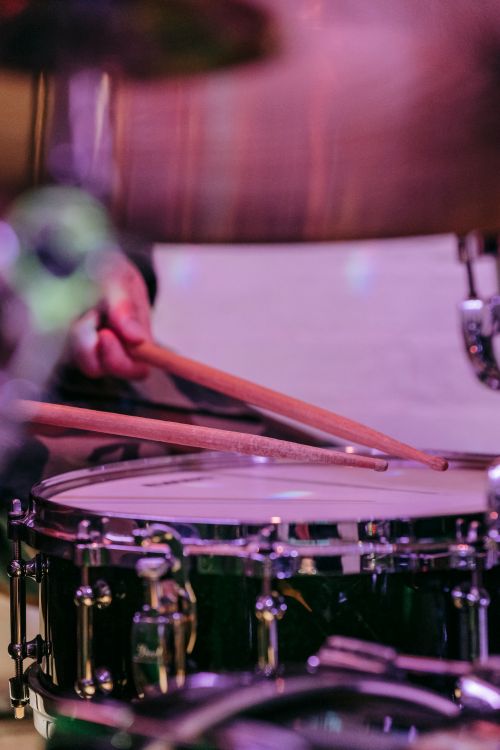 Free Close-up shot of a drummer playing a drum kit with vibrant lighting and focus on the hands. Stock Photo