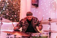 Man in Black and Brown Jacket Playing Drum