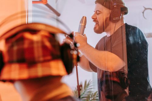 Free Adult male singer recording vocals in a studio, wearing headphones and using a microphone. Stock Photo