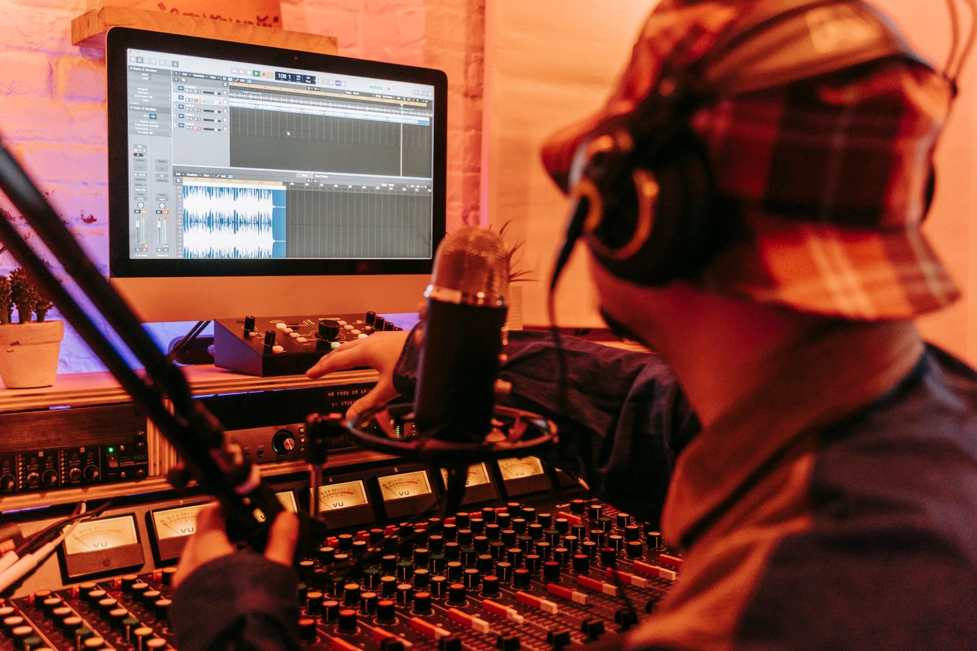 Music producer reviewing a recording project on a computer and studio console for a catalog inventory