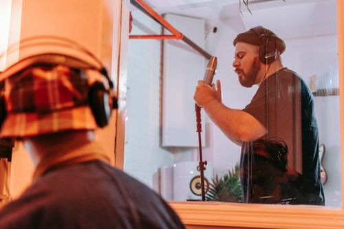 Free Musician performing in a modern recording studio with a condenser microphone. Stock Photo