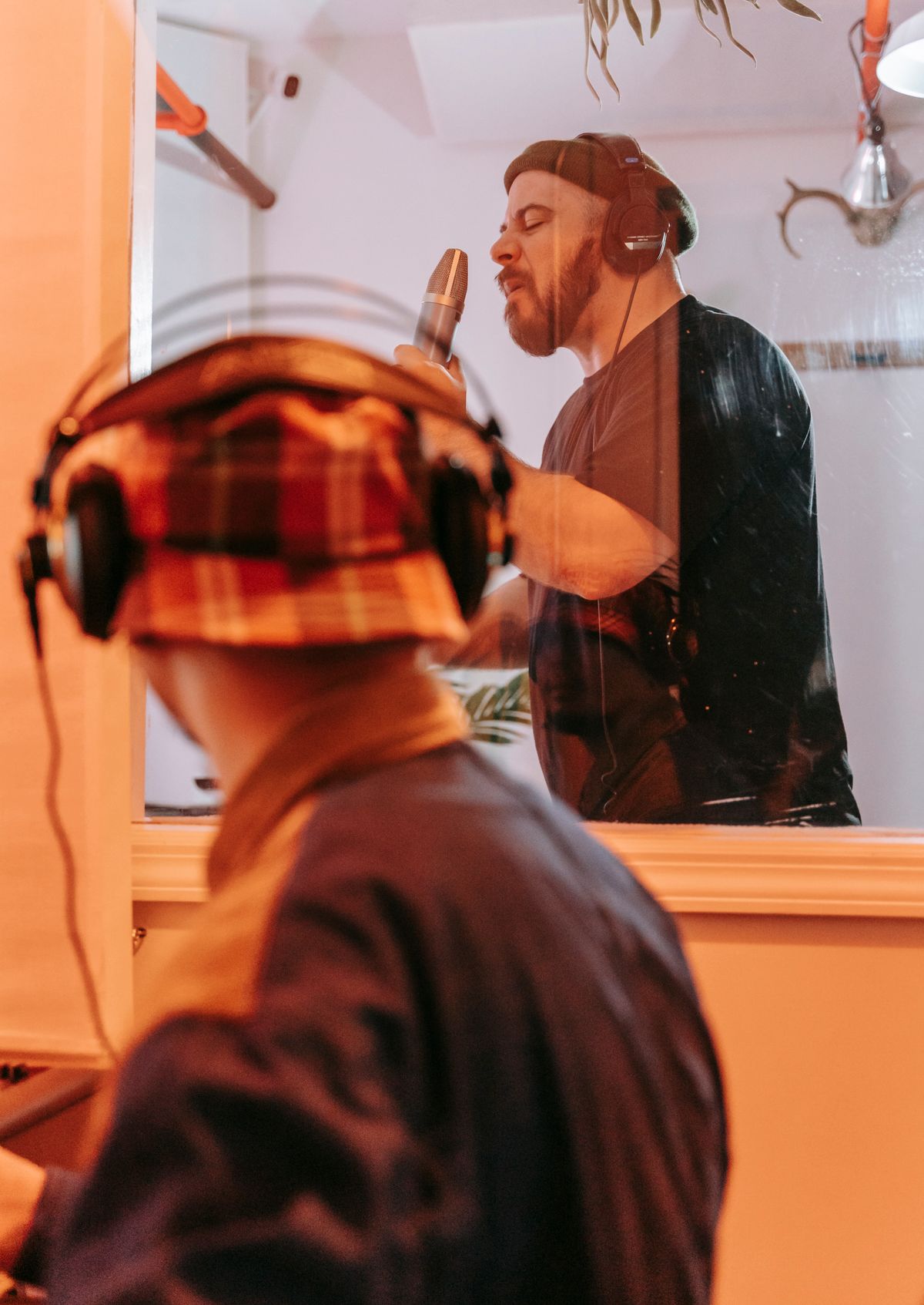 Director guiding a voice artist through the booth window