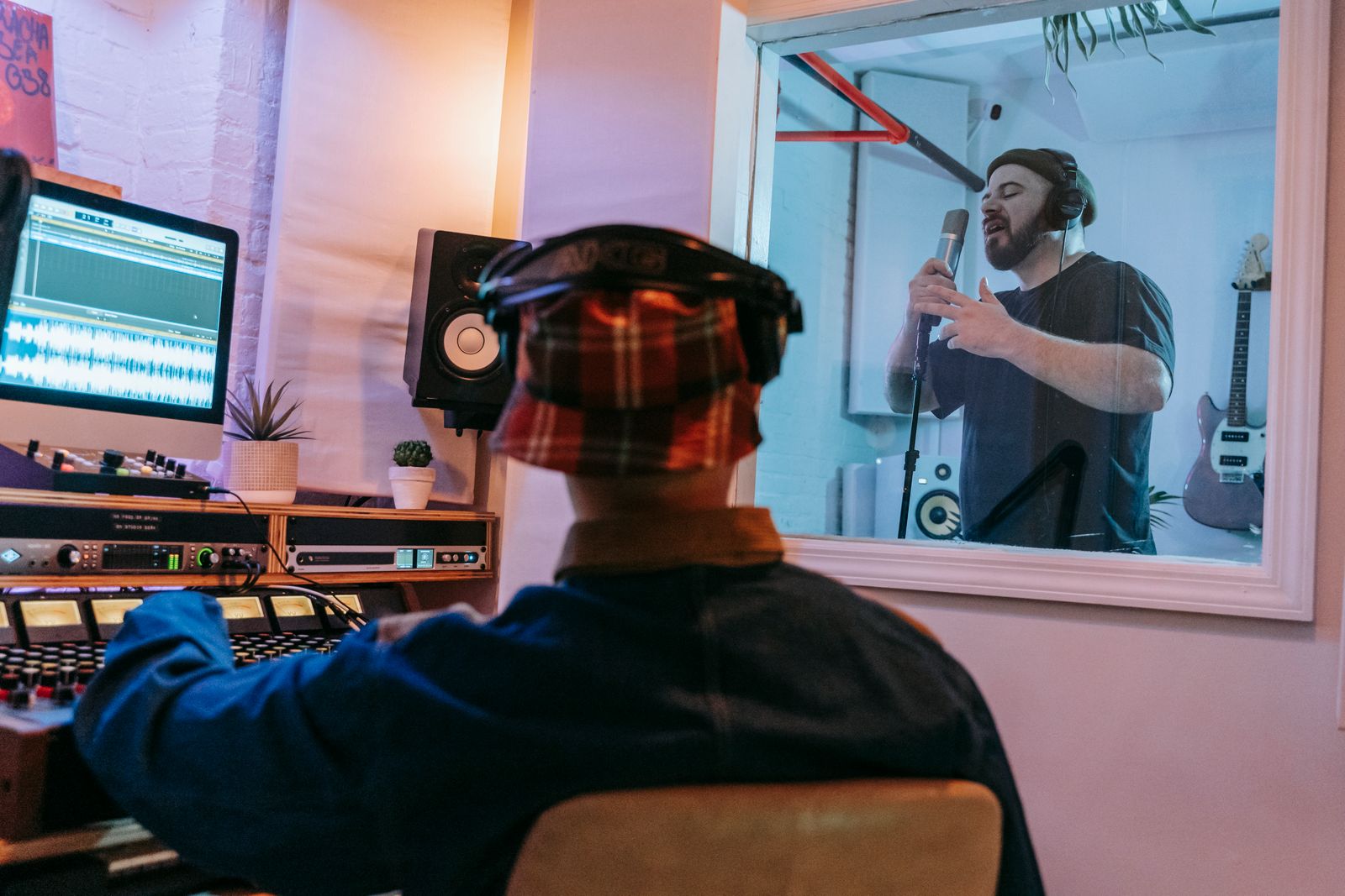 Audio engineer monitoring a singer during a studio recording session