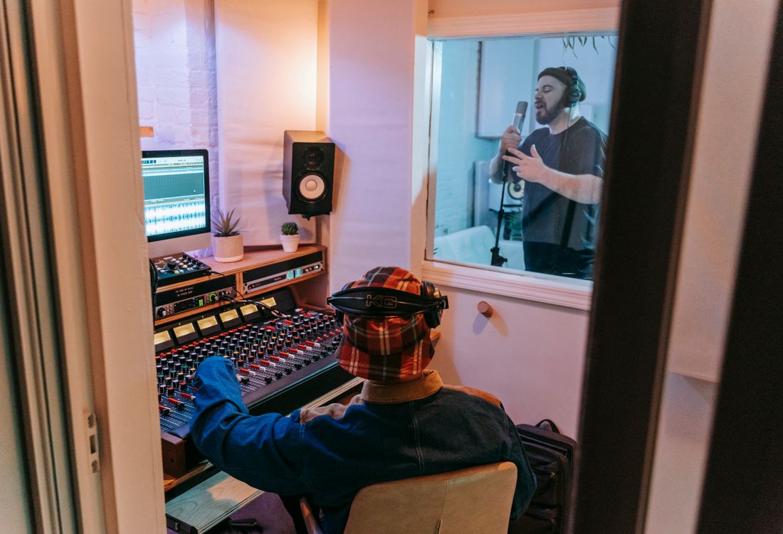 Régie du studio et chanteur visible derrière la vitre de la cabine