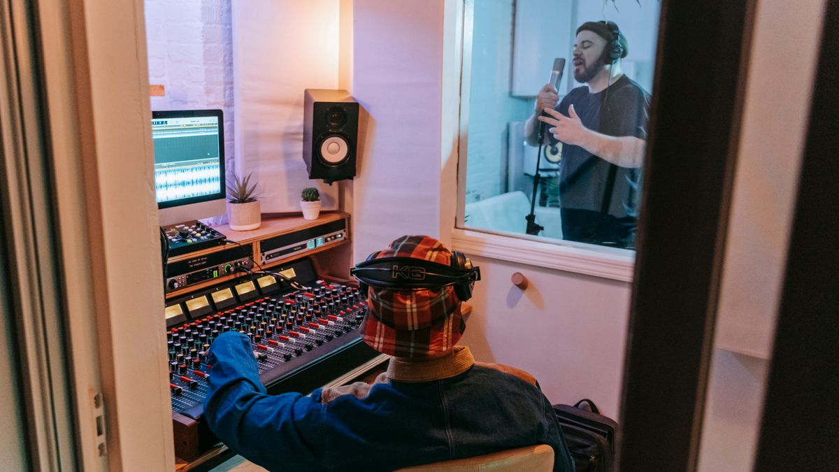Musicians and an audio engineer working in a recording studio