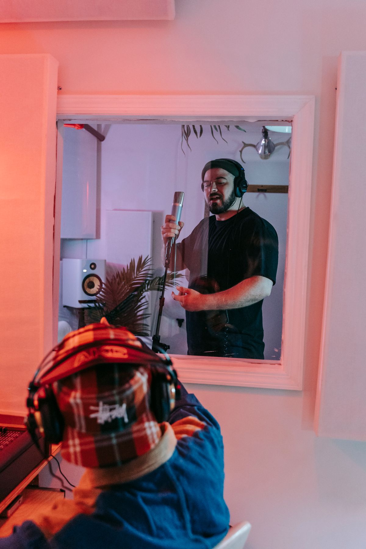 Singer inside the vocal booth seen through the control-room glass