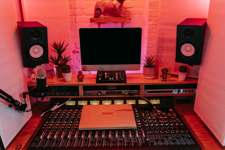 Sound Mixing Console On Desk With Computer Screen And Speakers