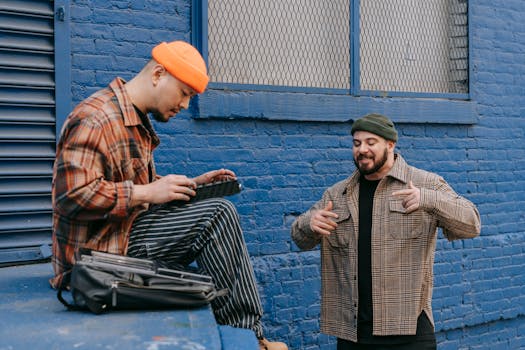 Two men enjoying a casual music session against a vibrant blue wall.