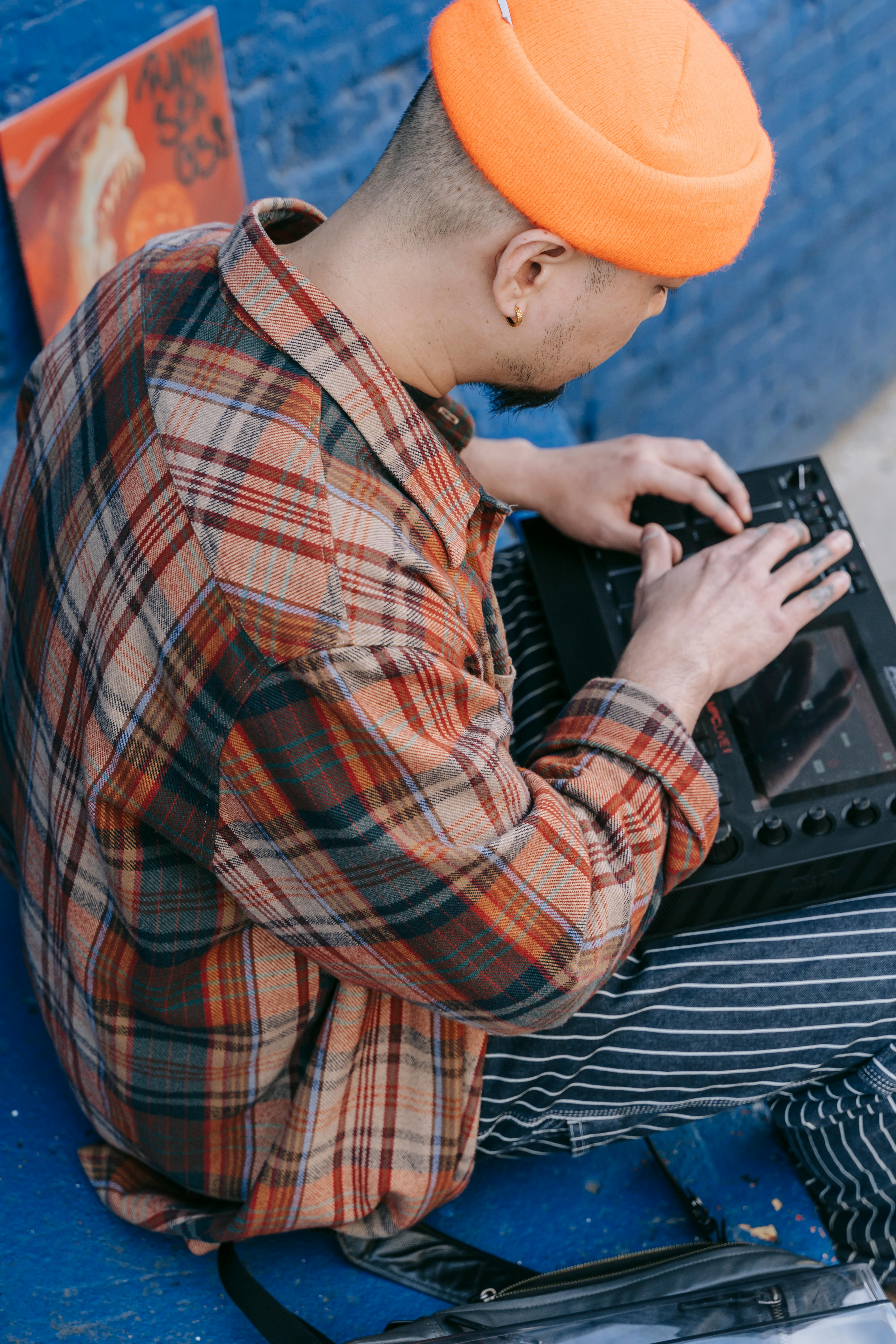 man in orange hat mixing music outdoors