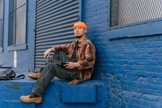 Man in Shirt Sitting Against Blue Wall