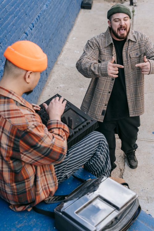 Free Two men engaging in urban music creation with a portable mixer outdoors. Stock Photo