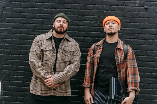 Two Men Wearing Casual Clothing Standing at Brick Wall