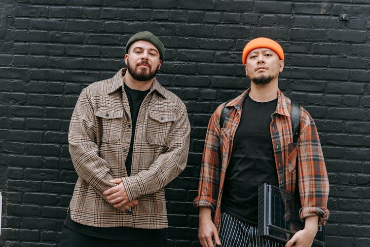 Two Men Wearing Casual Clothing Standing At Brick Wall