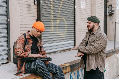 Free Two street musicians collaborate outside, discussing music and sound mixing. Stock Photo
