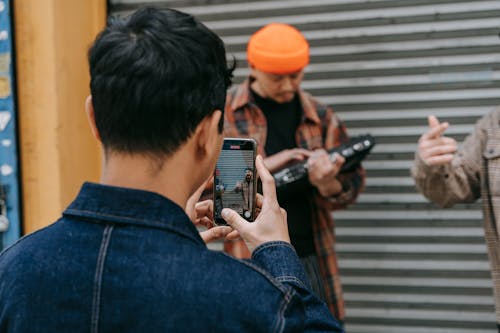 Man Wearing Denim Jacket Taking Photo of Two Men