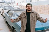 Man in Plaid Shirt with Gray Beanie Standing Beside a Blue Car