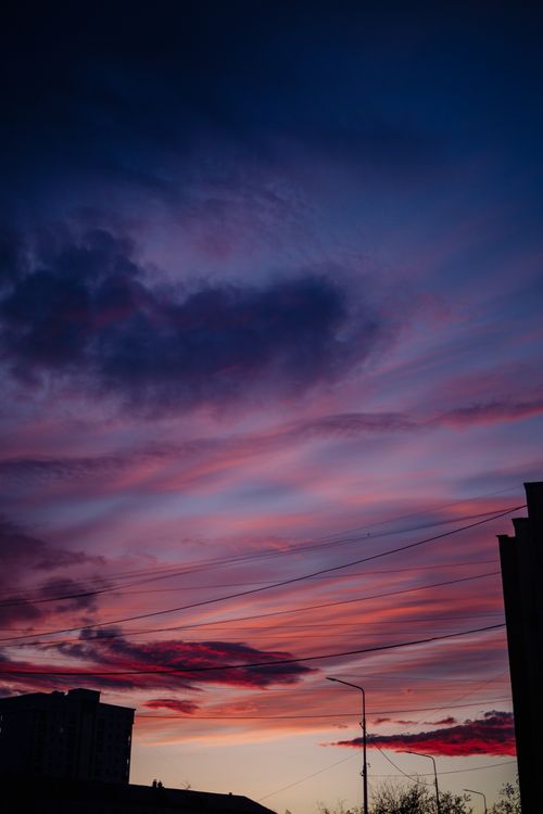 Free A breathtaking view of a colorful sky during dusk, featuring silhouettes of urban buildings. Stock Photo