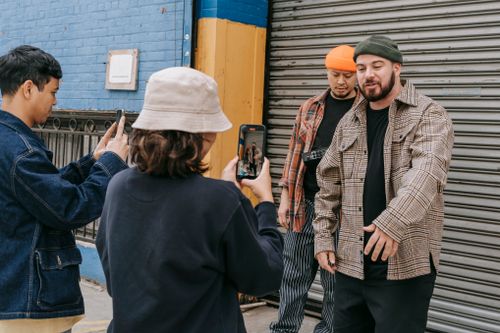 Free Group of young adults engaging in street photography with smartphones in an urban setting. Stock Photo
