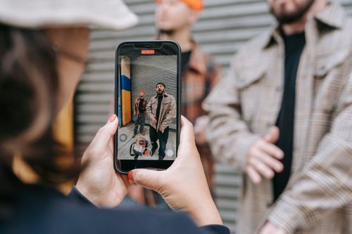 Free A person captures candid street moments with a smartphone, highlighting urban lifestyle and technology. Stock Photo