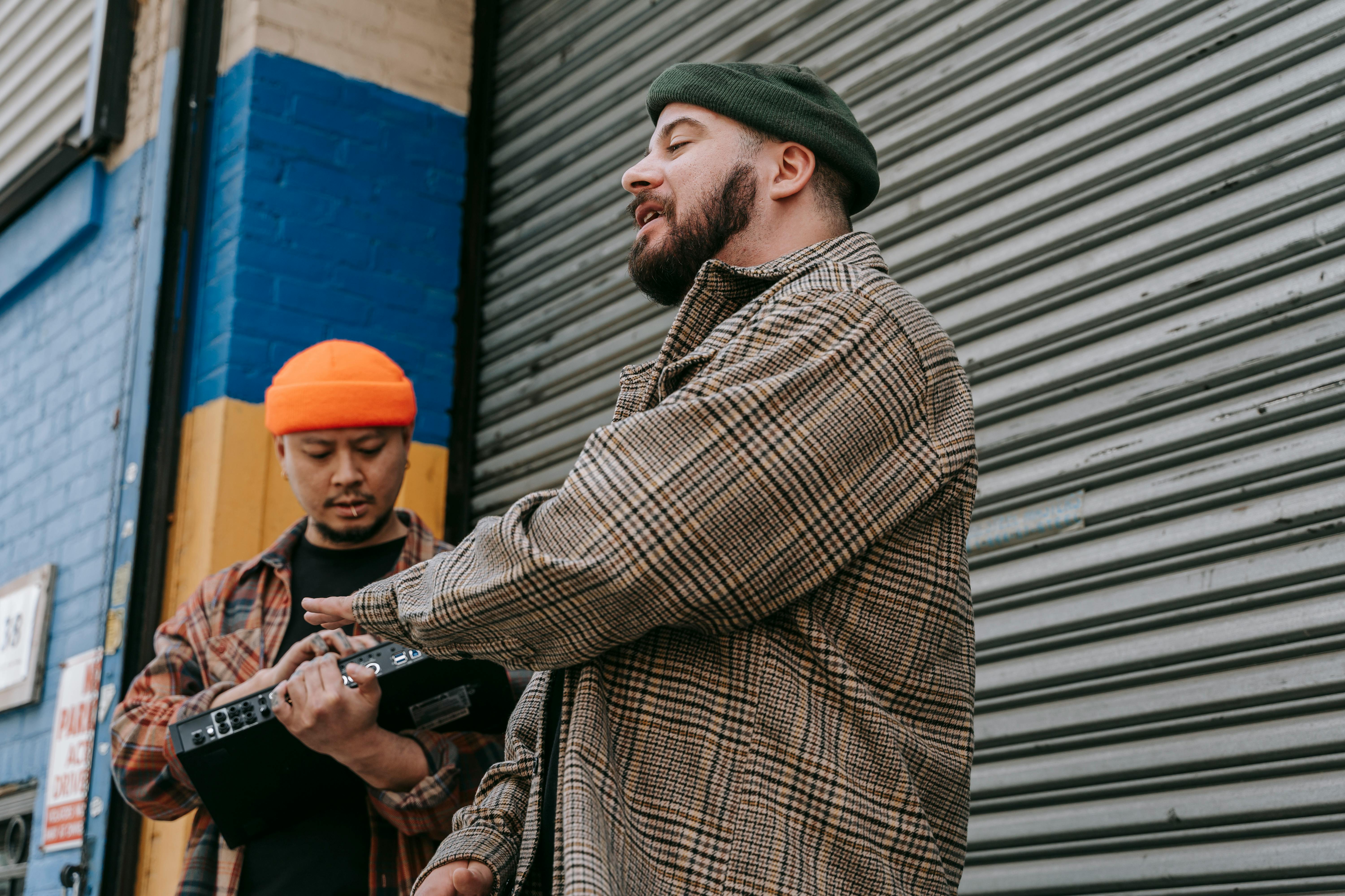 Two musicians collaborating with a sound mixing console in an urban street setting.