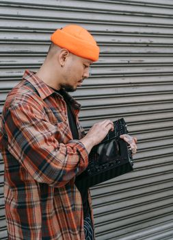 Young music producer using a console outdoors, capturing creative urban vibes.