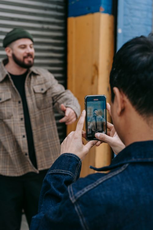 Free Young man capturing video of friend with a smartphone outdoors. Stock Photo