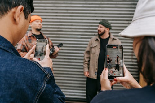 People Taking Photo of Two Men in Plaid Shirts with Beanies