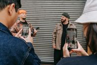 People Taking Photo of Two Men in Plaid Shirts with Beanies