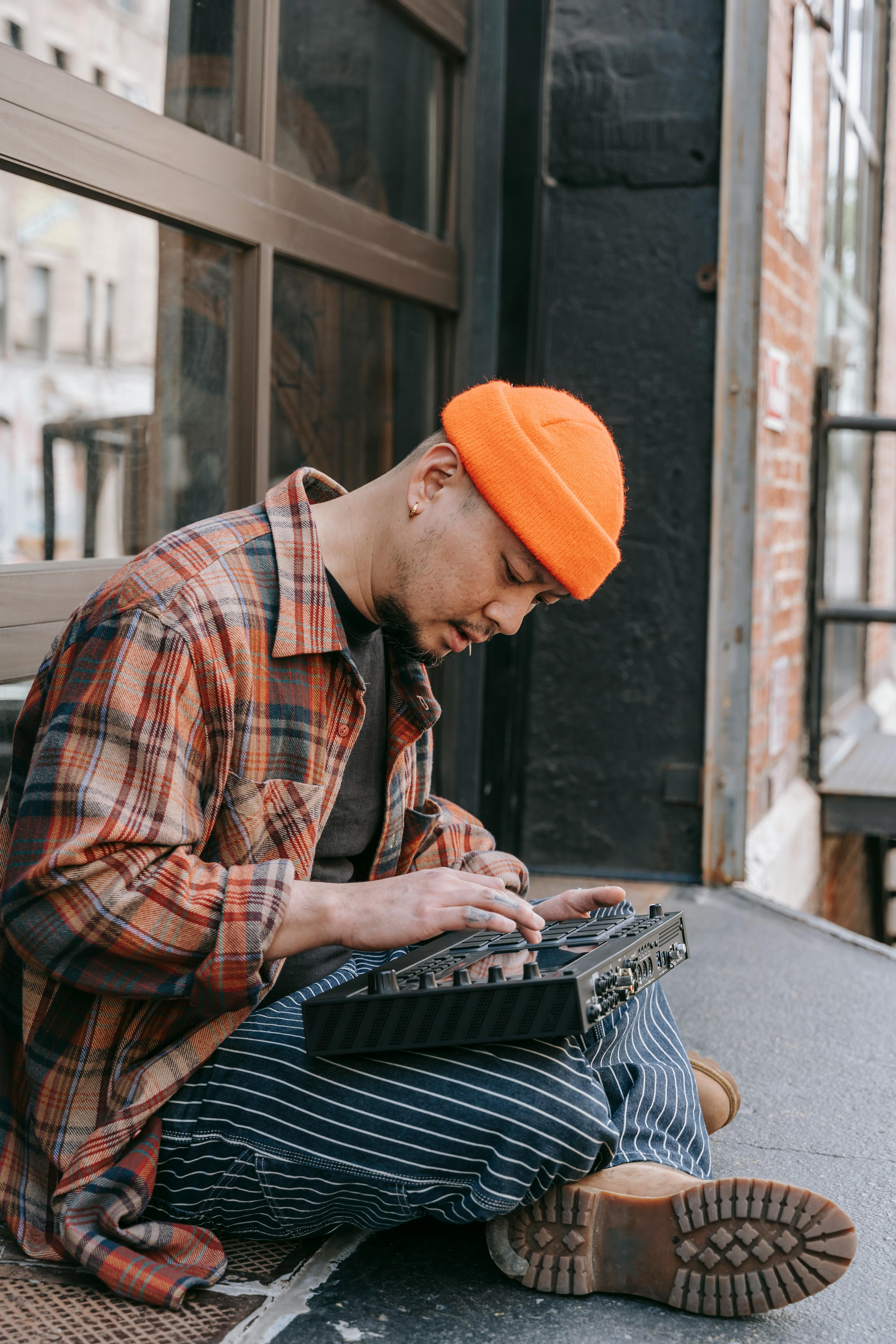 Young man mixes music on console outdoors, creating vibrant beats.