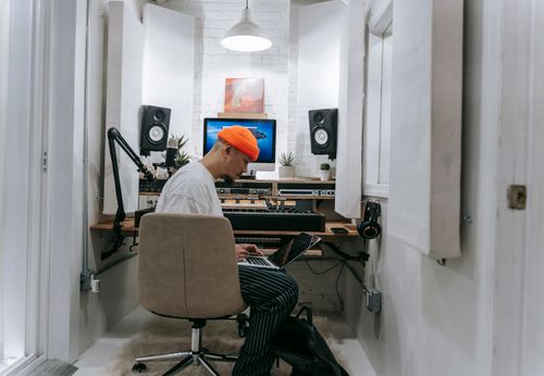 Free An adult male focuses on music production in a sleek, white recording studio setting. Stock Photo