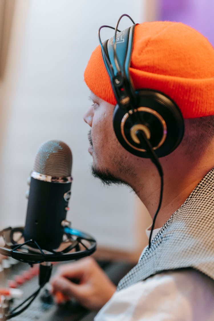 Profile Of A Man Wearing An Orange Hat And Headphones With Microphone