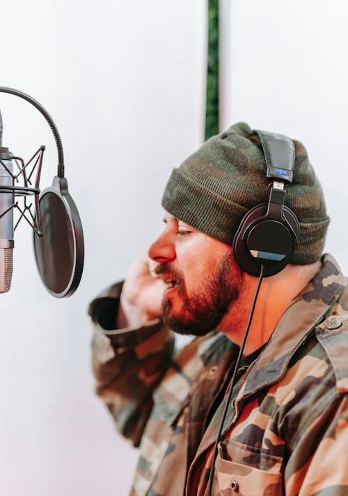 Man in Green and Brown Camouflage Jacket Wearing Black Headphones