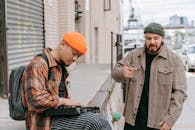 Man in Black and Brown Plaid Coat and Orange Knit Cap Standing Beside Man in Black