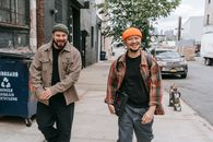 A Man in Green Knit Cap Walking Beside a Man in Orange Knit Cap on the Sidewalk