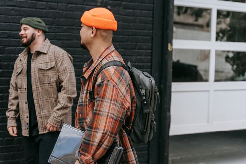 Free Two men in plaid shirts and knit caps, laughing in an urban setting. Stock Photo