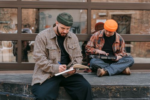 Free Two male musicians writing and creating music outside in a casual urban setting. Stock Photo