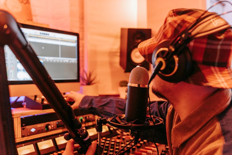 Orange Toned Image Of A Man Wearing A Hat And Headphones In A Recording Studio