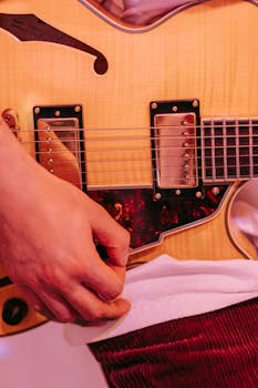 Detailed close-up of a musician's hand playing an electric guitar, emphasizing musical elements.