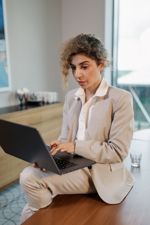 Free Businesswoman in office using a laptop for remote work, sitting comfortably. Stock Photo