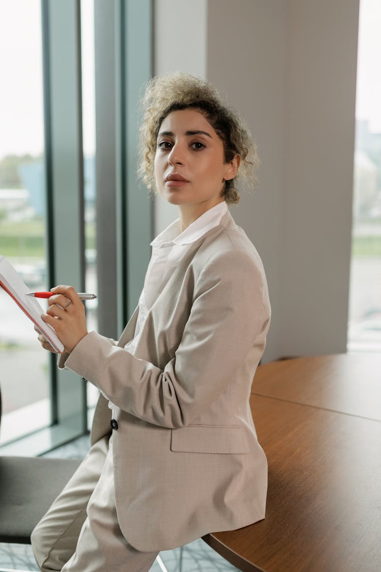 Woman In Beige Blazer Holding A Pen And Notebook