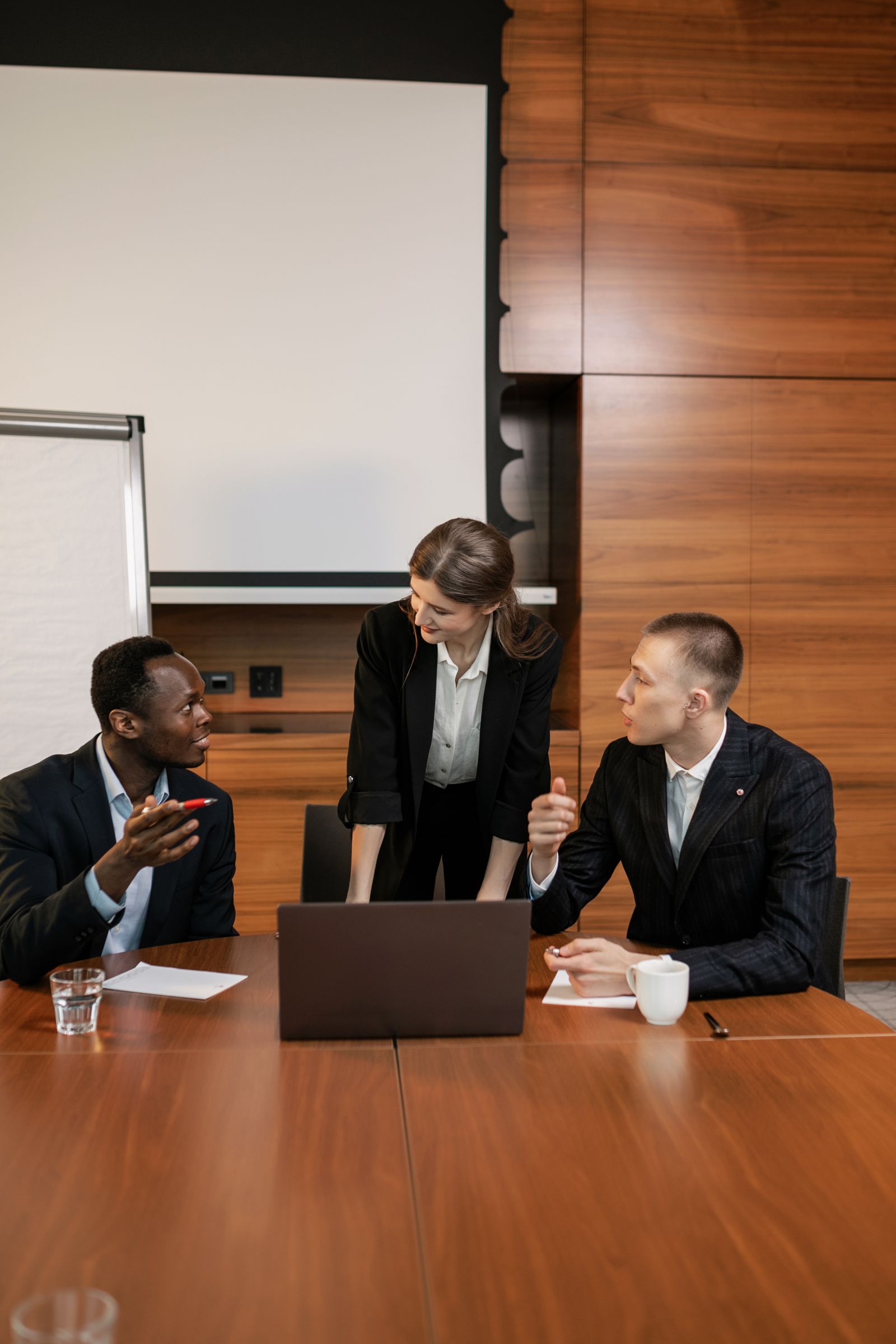 Professional team discussing strategy around a laptop and business documents