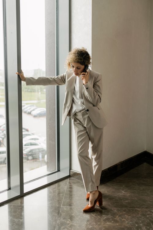 Free Confident businesswoman in corporate attire talking on phone by the window. Stock Photo